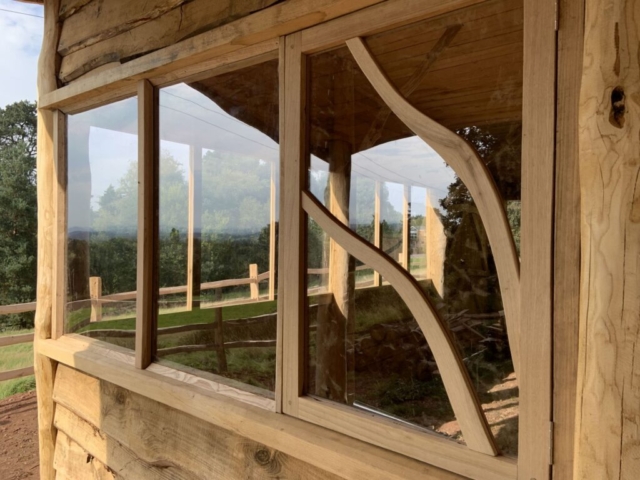 Curvy glazing bars break up the square windows Chestnut, Oak and Larch cladding were used to build this outdoor classroom in Monm